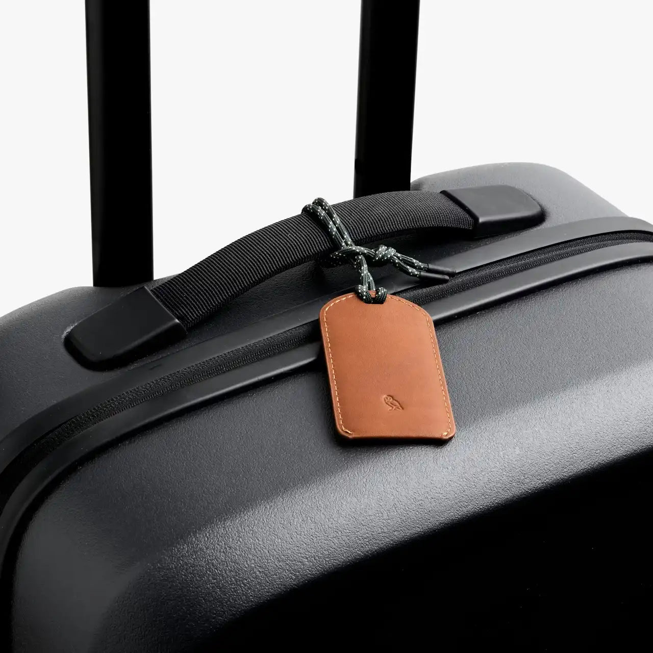 Bellroy kuffertmærke i brunt læder på sort Bellroy Carry On