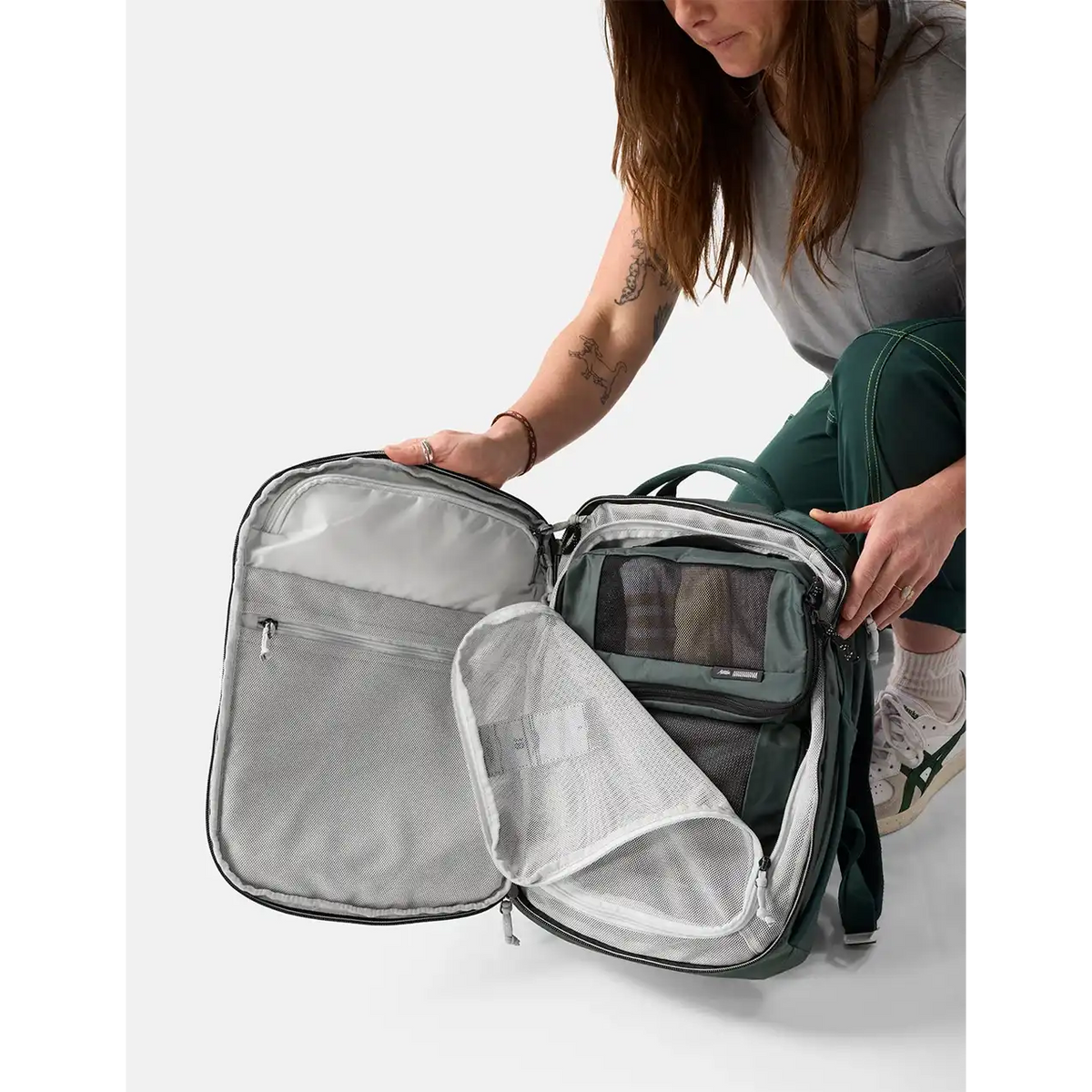 Kvinde med Matador 18L personal item rygsæk, grøn, åben med packing cubes