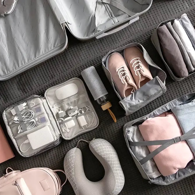 en åben kuffert med diverse rejse tilbehør såsom packing cubes og en nakkepude