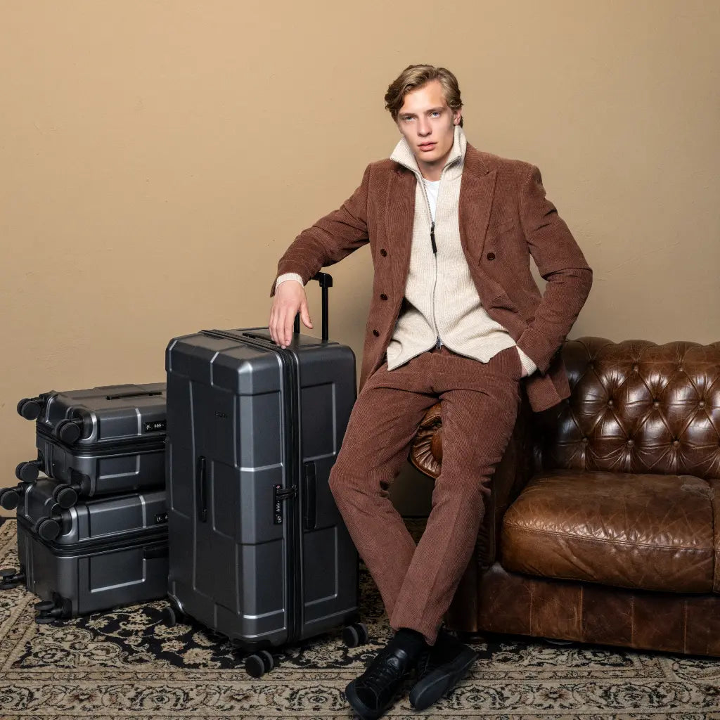 Mand som sidder i sofa ved siden af trunk kufferter
